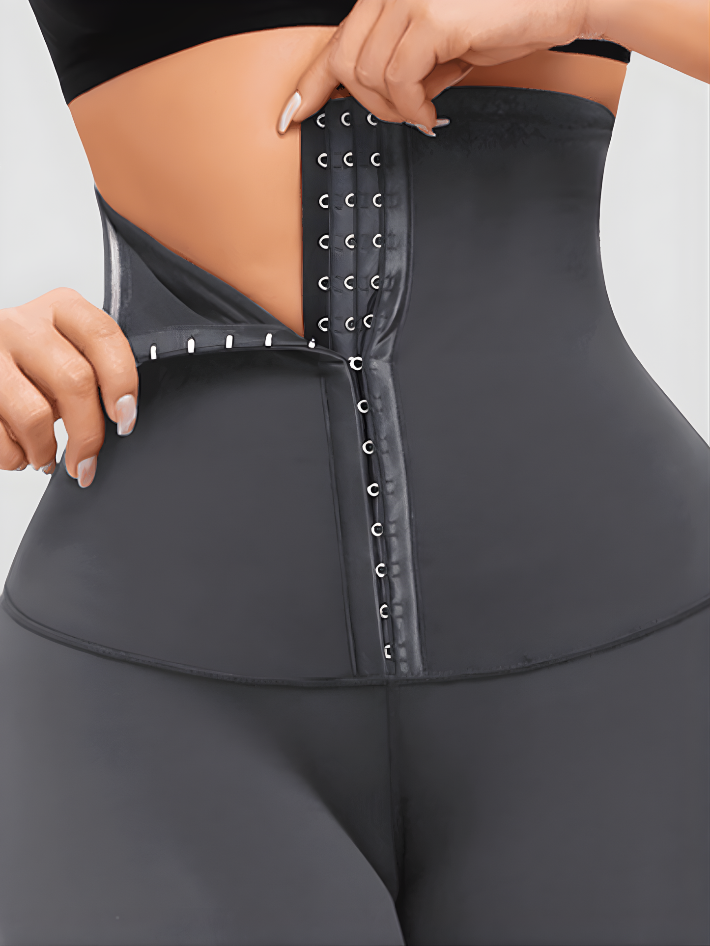 Woman wearing high-waisted gray waist-training leggings with a 3-level corset-style closure to flatten her tummy and sculpt her curves.
