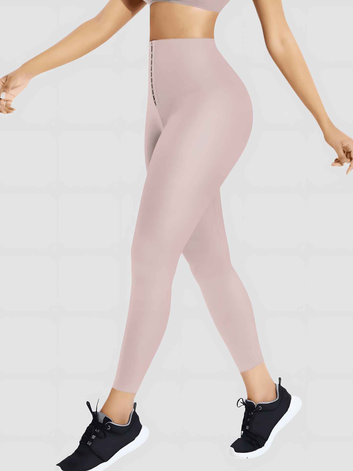 Woman walking in high-waisted light pink corset style leggings designed for tummy control and waist training.