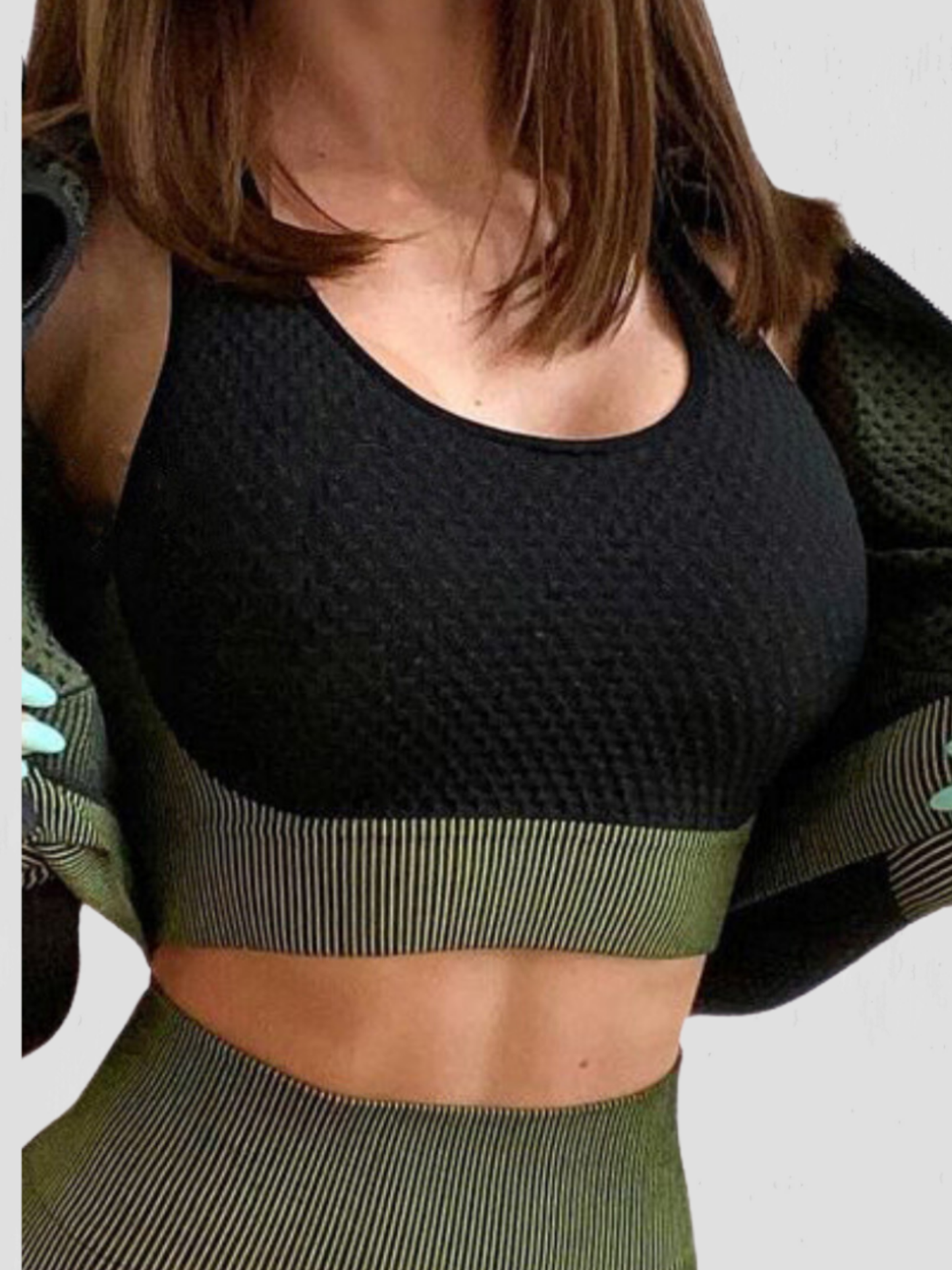 Woman wearing a black and green sports bra with matching leggings and jacket by BodyFlexx.