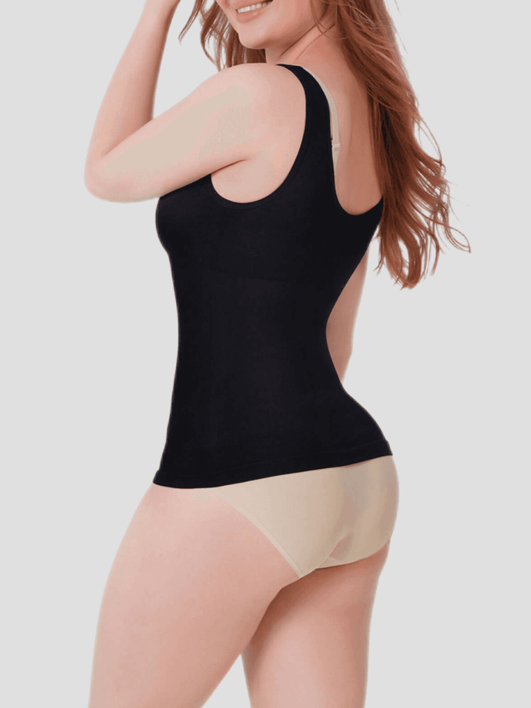 Woman wearing a black shaping tank top by BodyFlexx Shapewear and beige underwear showing off her curves.