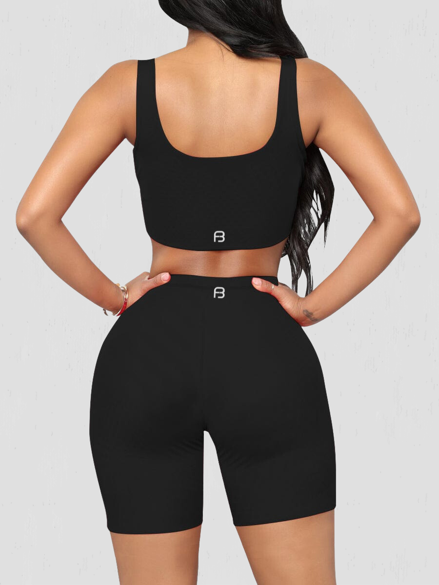 Woman wearing a black matching shorts and sports bra activewear set showing the BodyFlexx logo on the back.