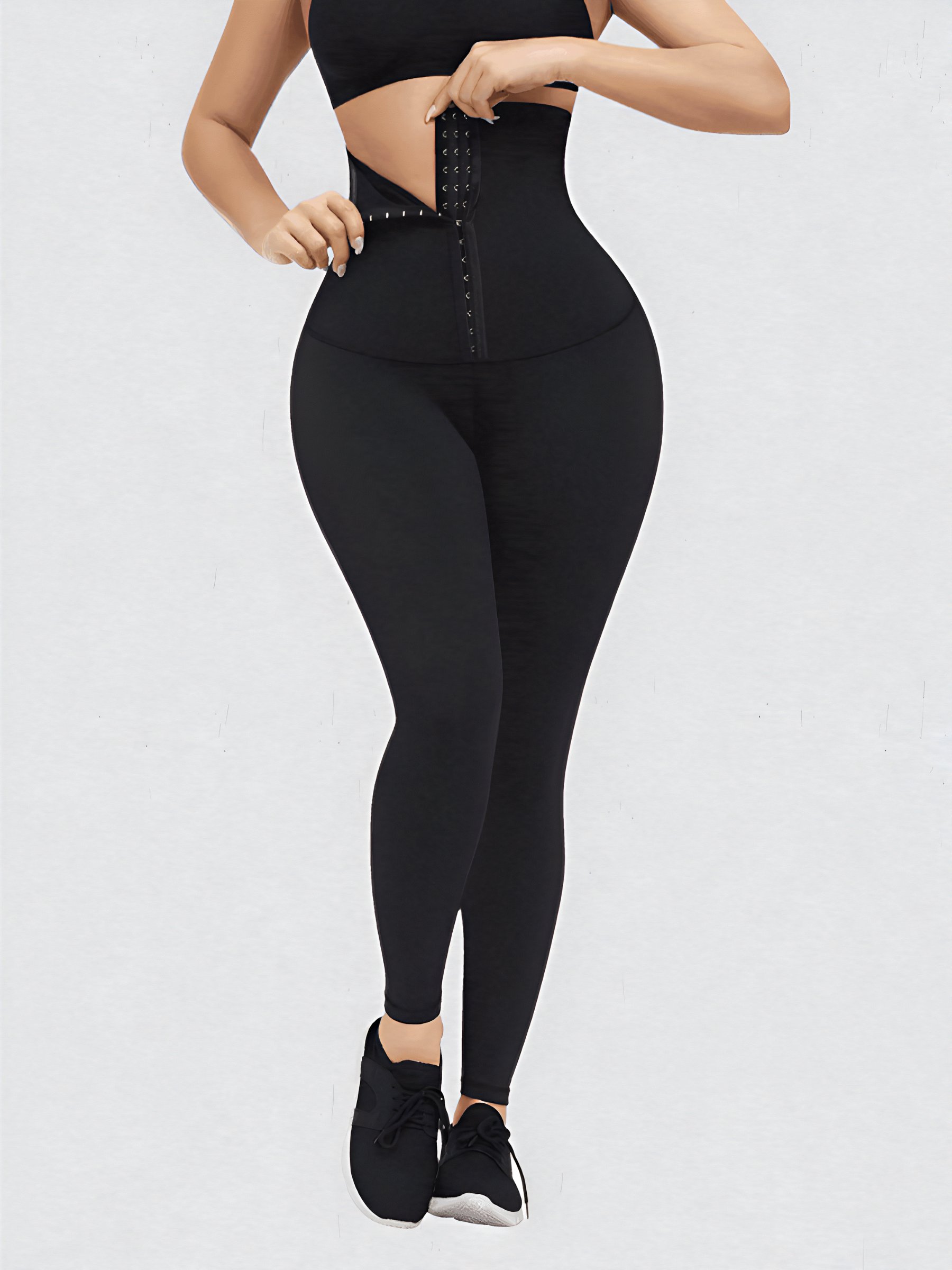 Woman wearing high-waisted black waist-training leggings with a corset-style closure to flatten her tummy and sculpt her curves.