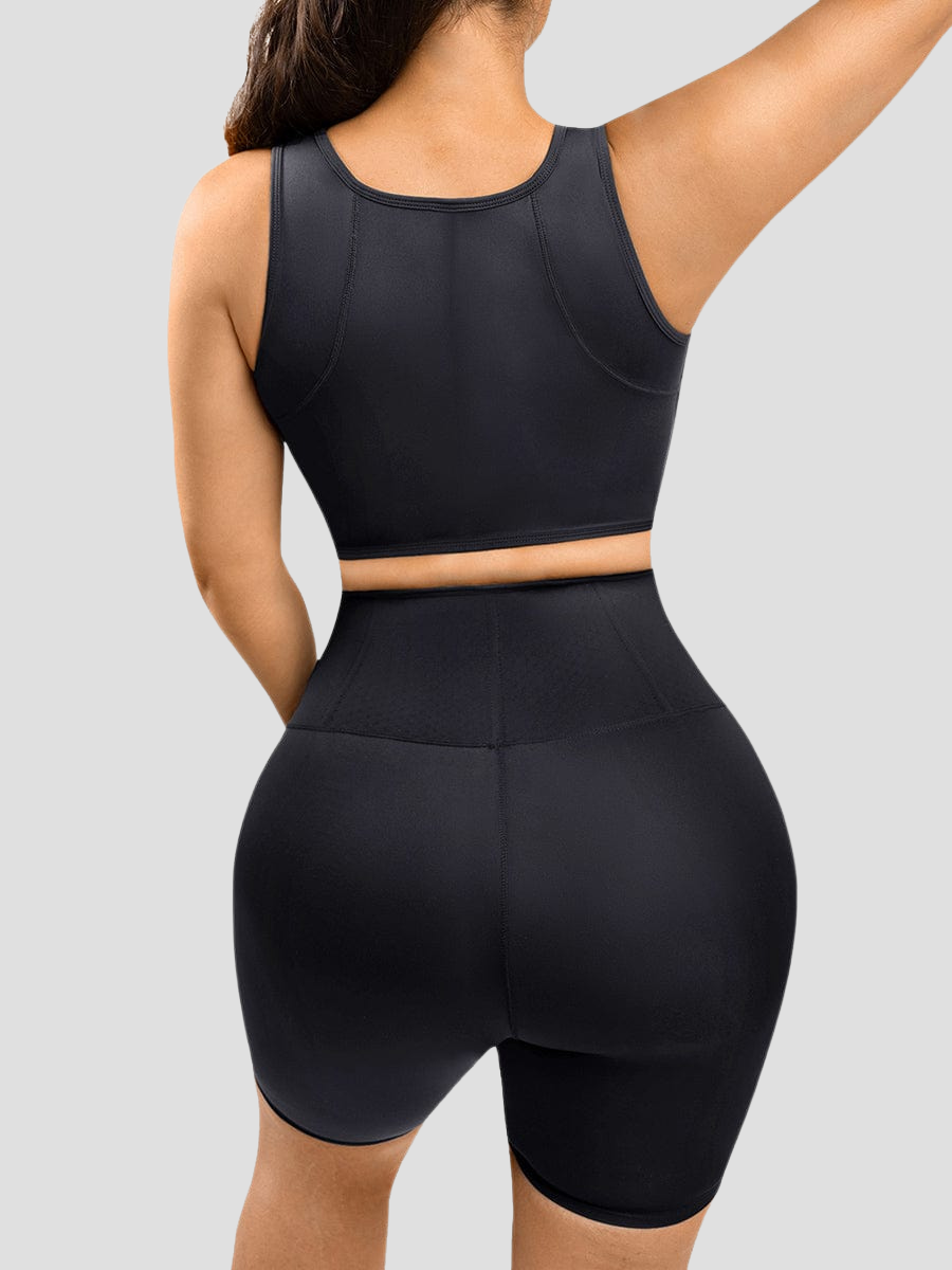 A woman stretching wearing a black sports bra top and matching shorts. She is showing the back which is designed with flexible boning to ease pain and provide posture correction.