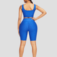 Woman standing backwards wearing a blue mid-thigh shorts and sports bra activewear set with a honeycomb pattern.