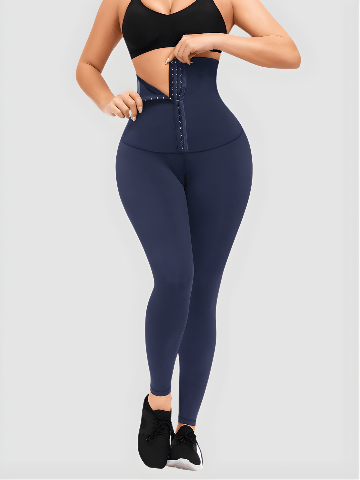 Woman wearing high-waisted blue waist training leggings with a corset-style closure to flatten her tummy and sculpt her curves.