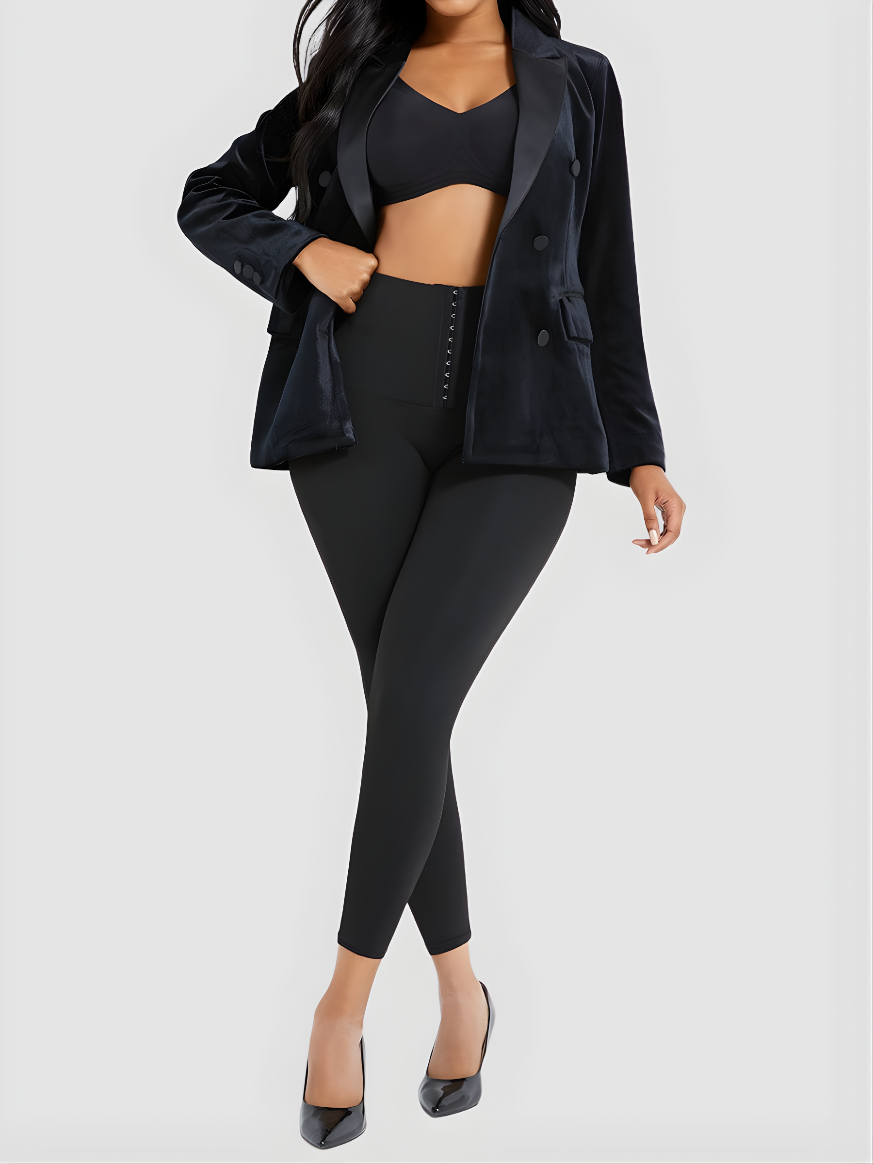 Woman wearing high waisted black corset leggings by BodyFlexx Shapewear with a black jacket and black heels.