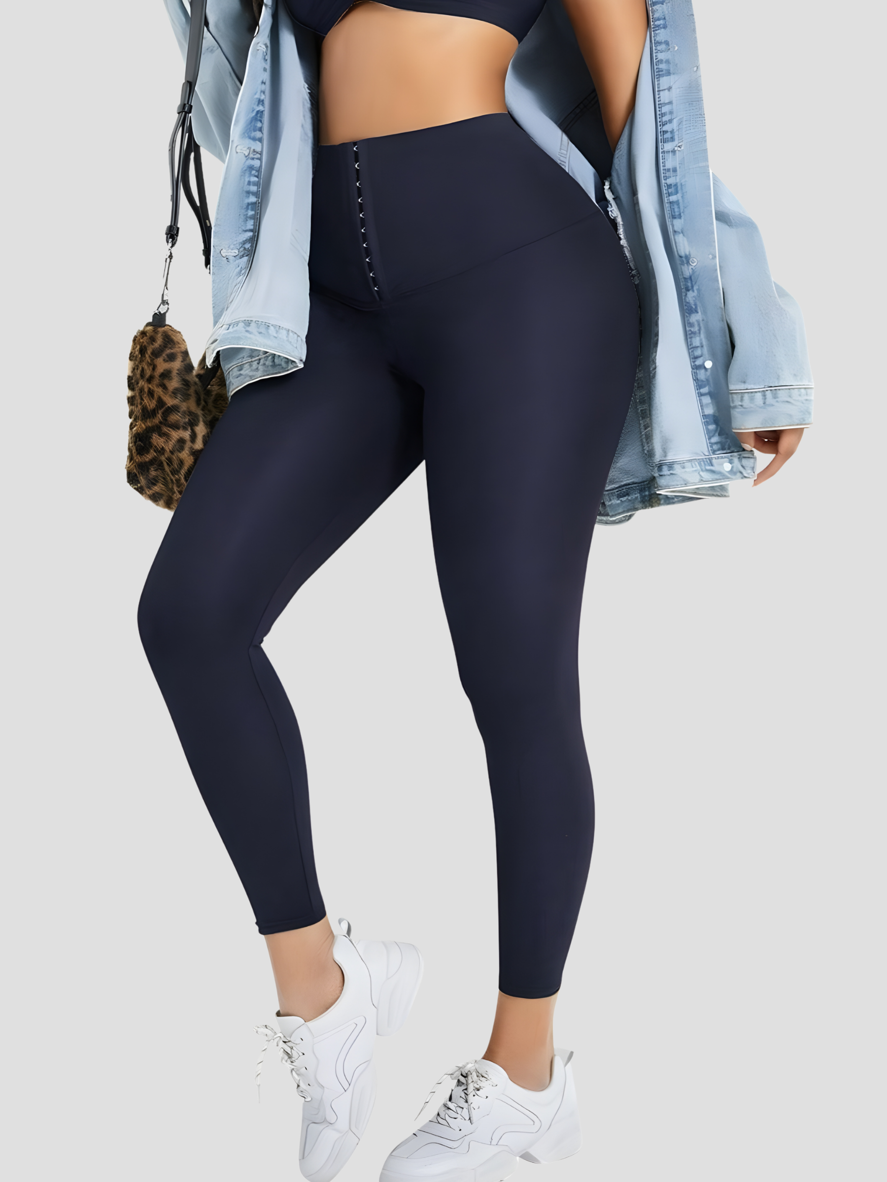 Woman wearing blue waist training leggings with a corset closure paired with a jean jacket.