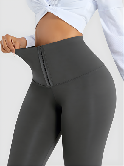 Woman posing wearing gray waist training corset leggings by BodyFlexx Shapewear and a white blouse.