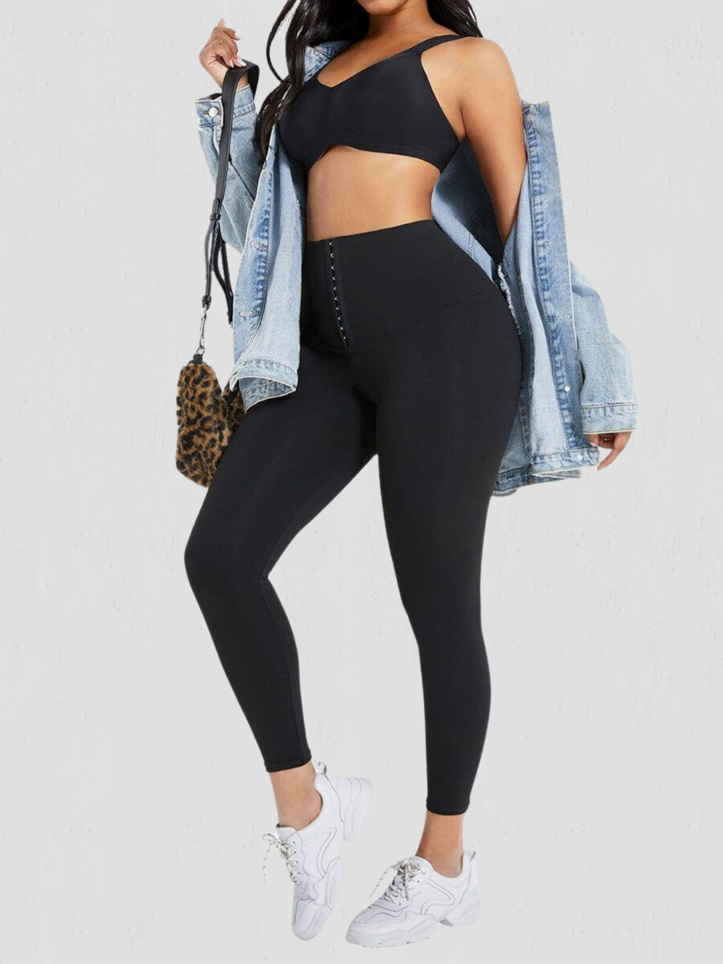 Woman posing wearing black waist-training corset leggings by BodyFlexx Shapewear with a jean jacket.