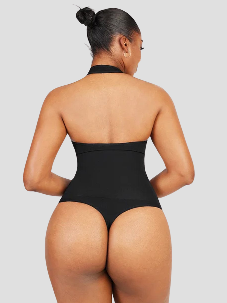 Woman wearing a black halter-style shapewear bodysuit with built-in removable bra padding and seamless thong design. She is posing showing the back view.