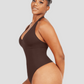 Woman wearing a brown halter-style shapewear bodysuit with built-in removable bra padding and seamless thong design. She is posing showing off her curves.