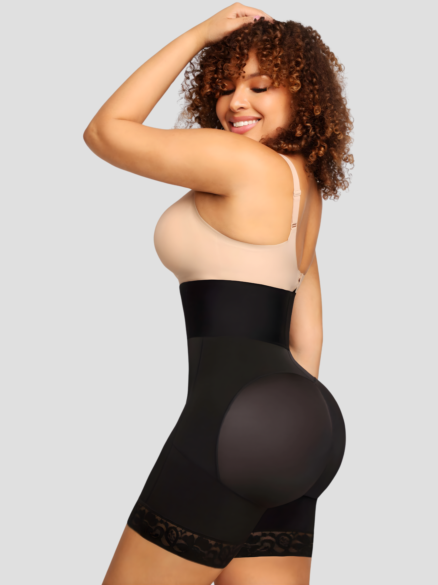 Woman posing in a black high-waisted Columbian faja corset shapewear with lace trim  showing off her lifted bum.