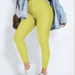 Woman posing wearing yellow waist-training corset leggings by BodyFlexx Shapewear with a jean jacket.