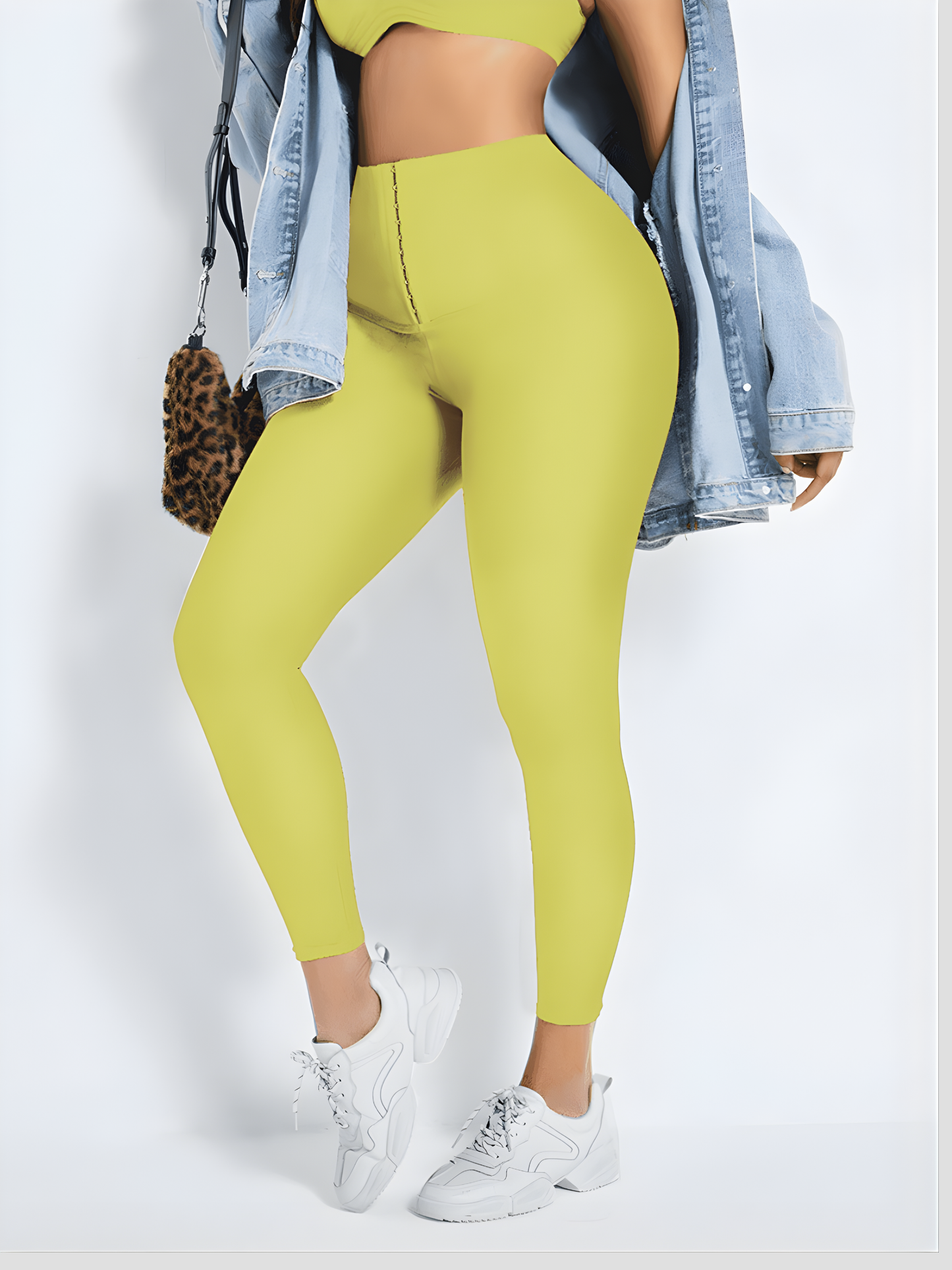 Woman posing wearing yellow waist-training corset leggings by BodyFlexx Shapewear with a jean jacket.
