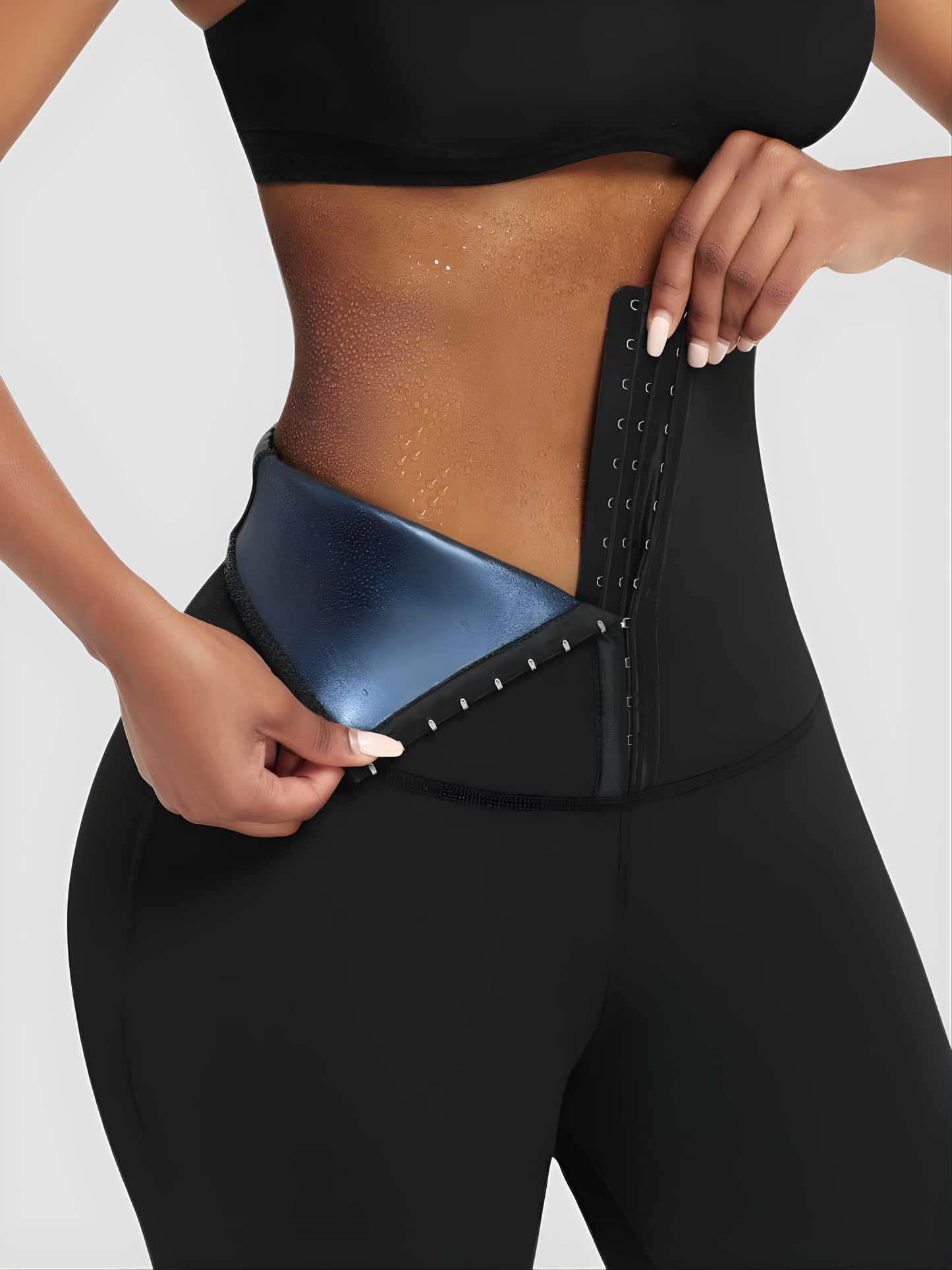 Woman wearing black BodyFlexx Waist-Training Sauna Leggings with the corset closure open showing a sweaty stomach after working out.
