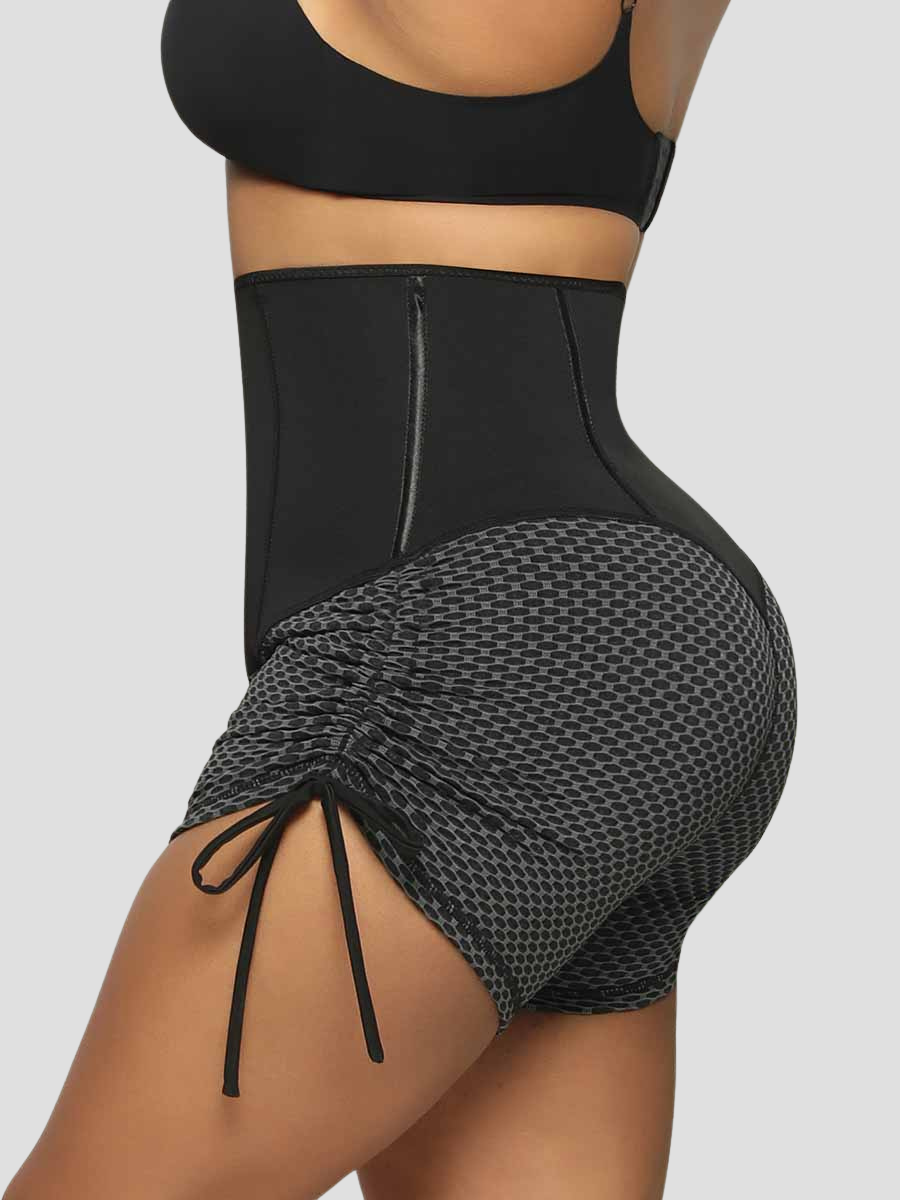 Close up side view of a woman wearing black and gray sauna activewear shorts with a textured honeycomb pattern and adjustable leg drawstrings.