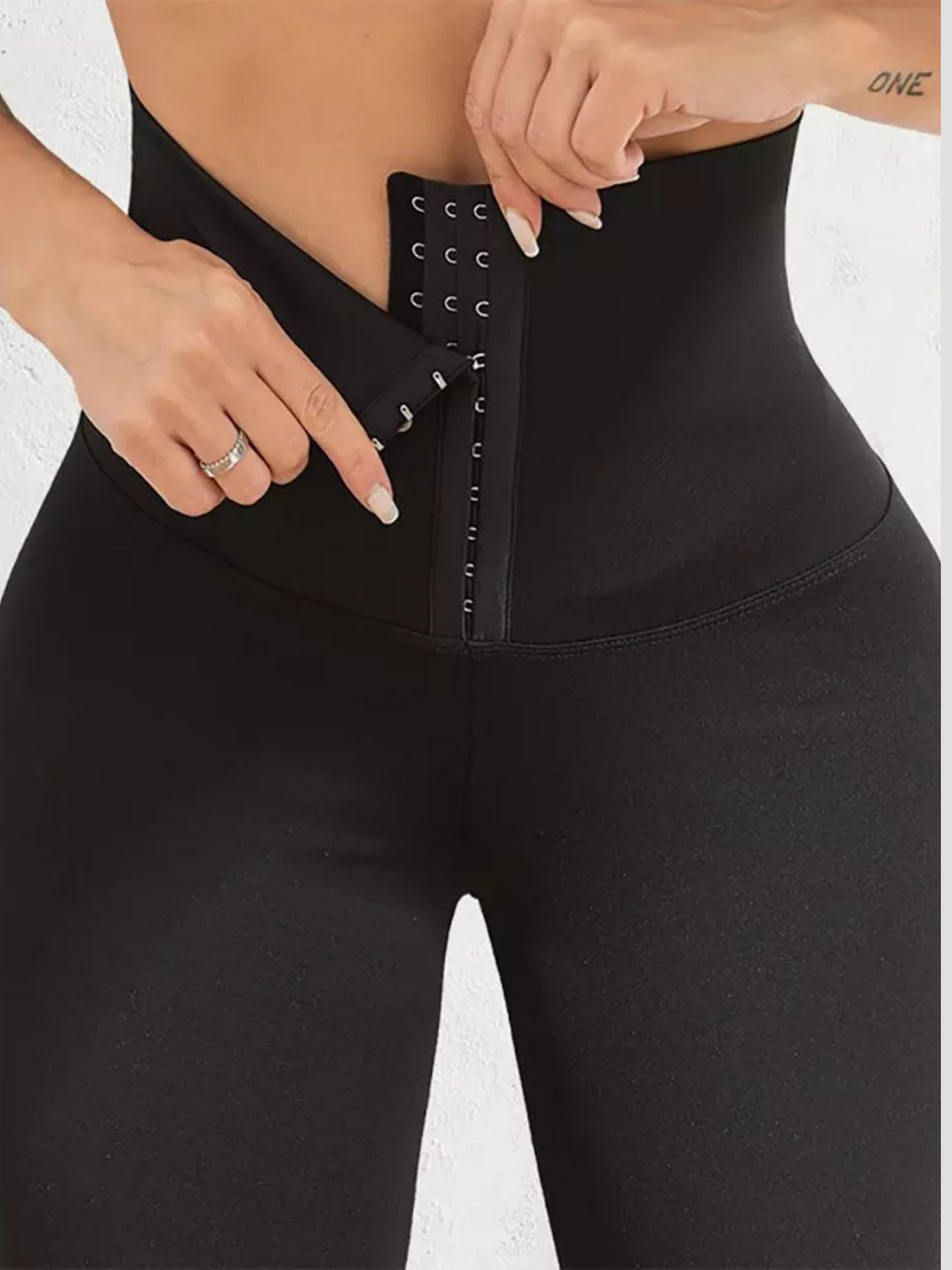 Woman wearing black waist trainer leggings with a corset closure designed for tummy-control and cellulite-smoothing by BodyFlexx Shapewear.