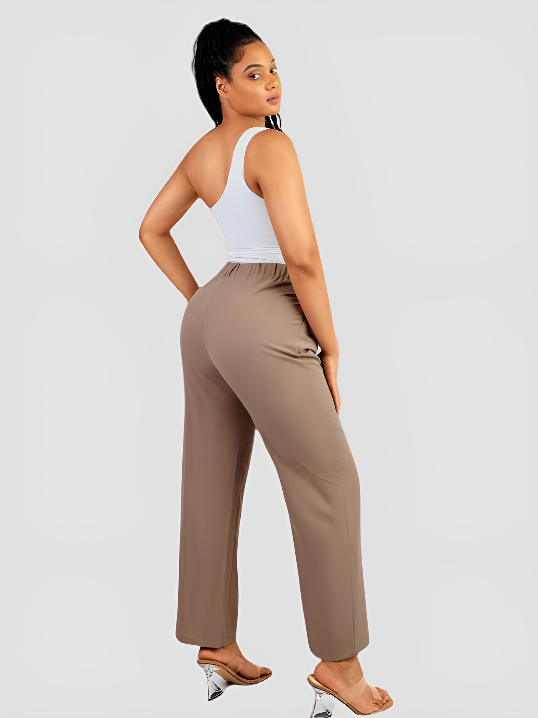 A woman wearing a white off-the-shoulder shaping bodysuit with built-in tummy-control shapewear paired with tan pants flaunting her curves.