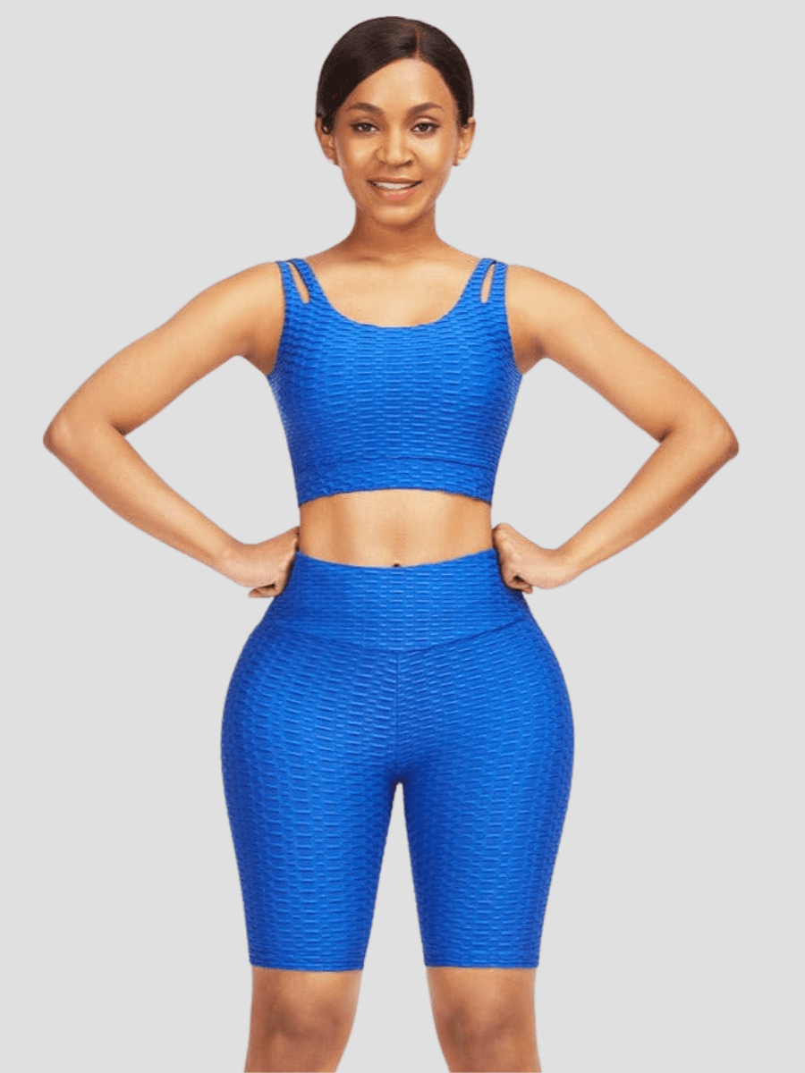 A woman wearing a blue high-waisted activewear shorts and a matching sports bra with a textured honeycomb pattern.