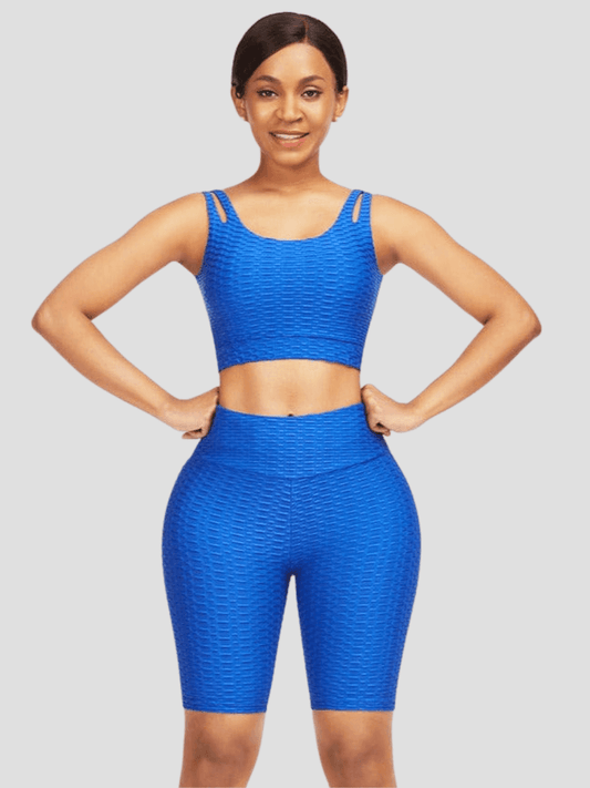 A woman wearing a blue high-waisted activewear shorts and a matching sports bra with a textured honeycomb pattern.