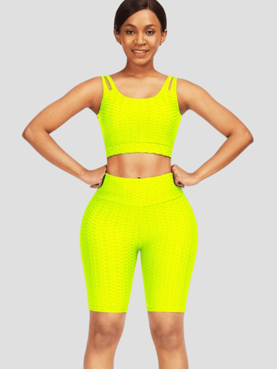 A woman wearing a yellow high-waisted activewear shorts and a matching sports bra with a textured honeycomb pattern.