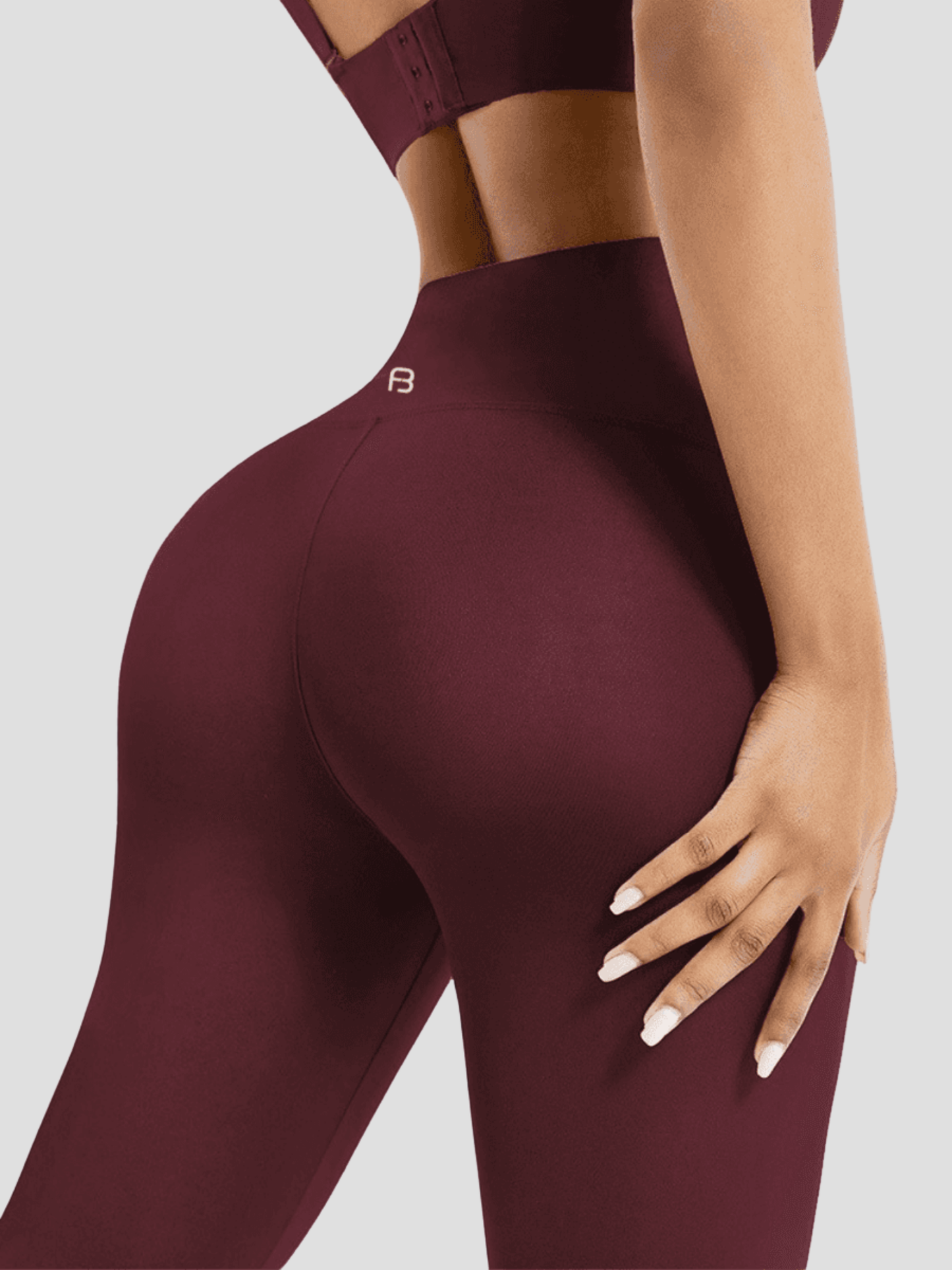 Woman standing backwards wearing red high-waisted corset leggings showing off her backside curves. You can see the BodyFlexx Shapewear logo on the mid-back of the leggings.