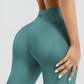 Woman standing backwards wearing teal high waisted, cellulite-smoothing leggings showing off her backside curves. You can see the BodyFlexx Shapewear logo on the mid-back of the leggings.