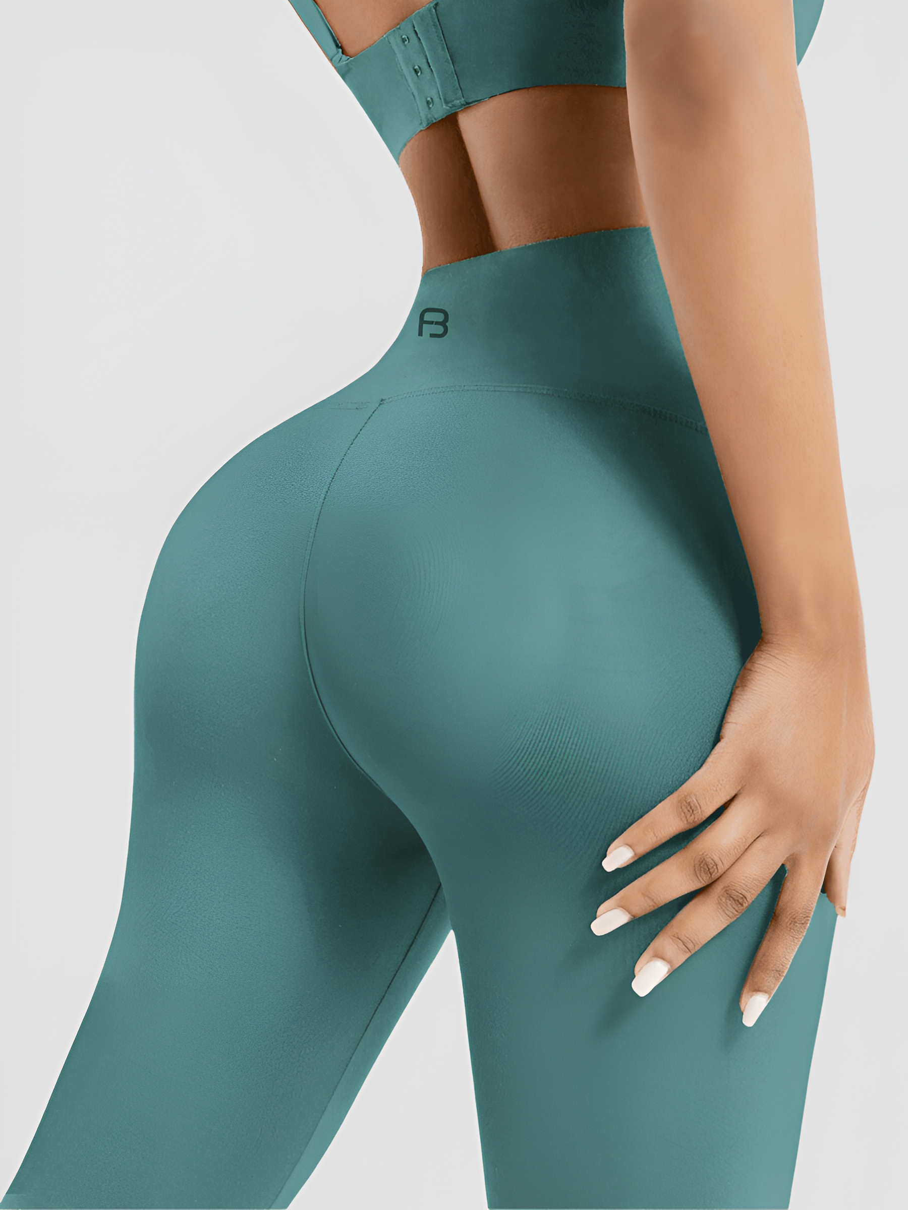 Woman standing backwards wearing teal high waisted, cellulite-smoothing leggings showing off her backside curves. You can see the BodyFlexx Shapewear logo on the mid-back of the leggings.