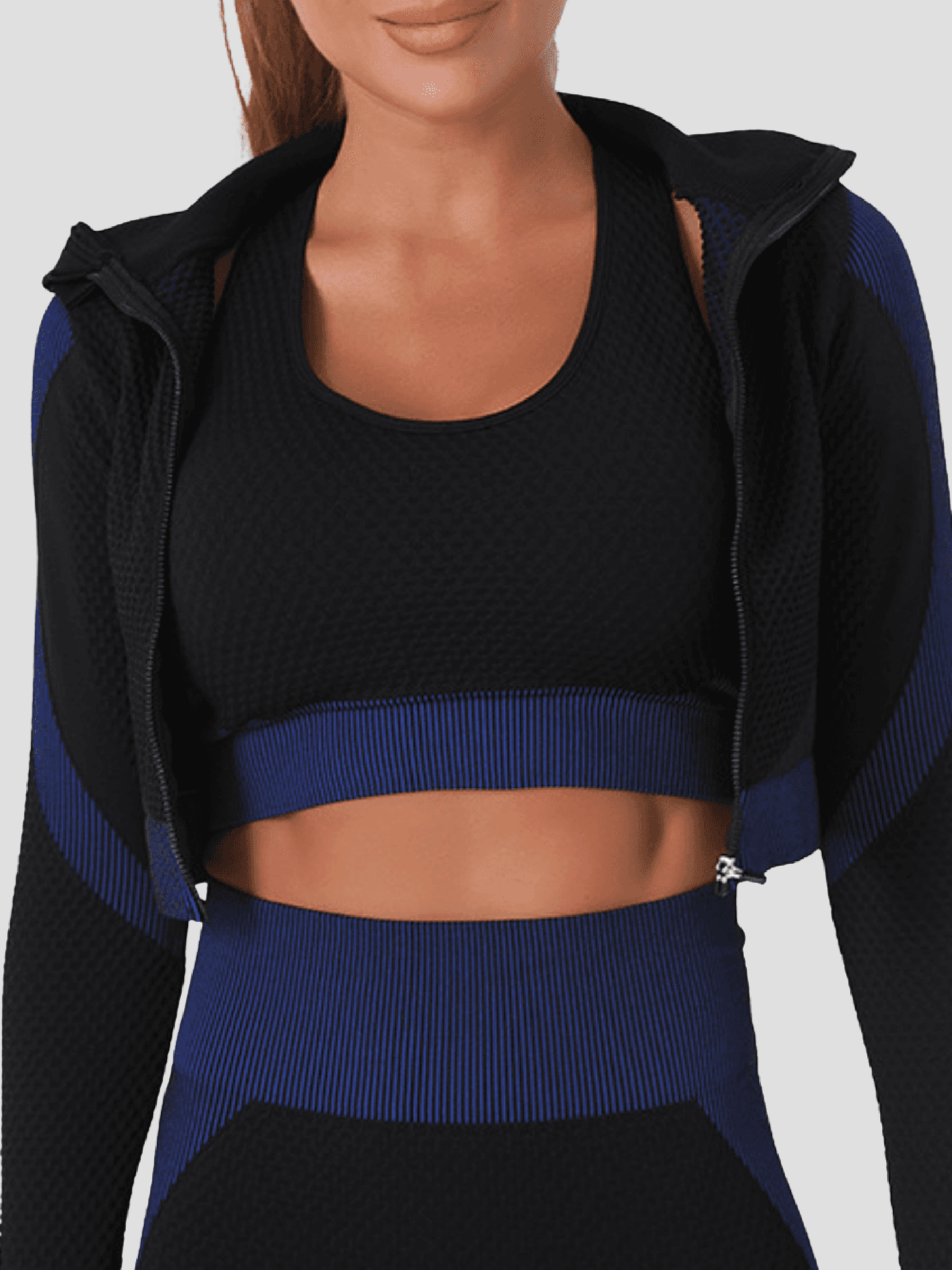 Woman wearing a blue and black zippered cropped a BBL jacket with a matching activewear top.