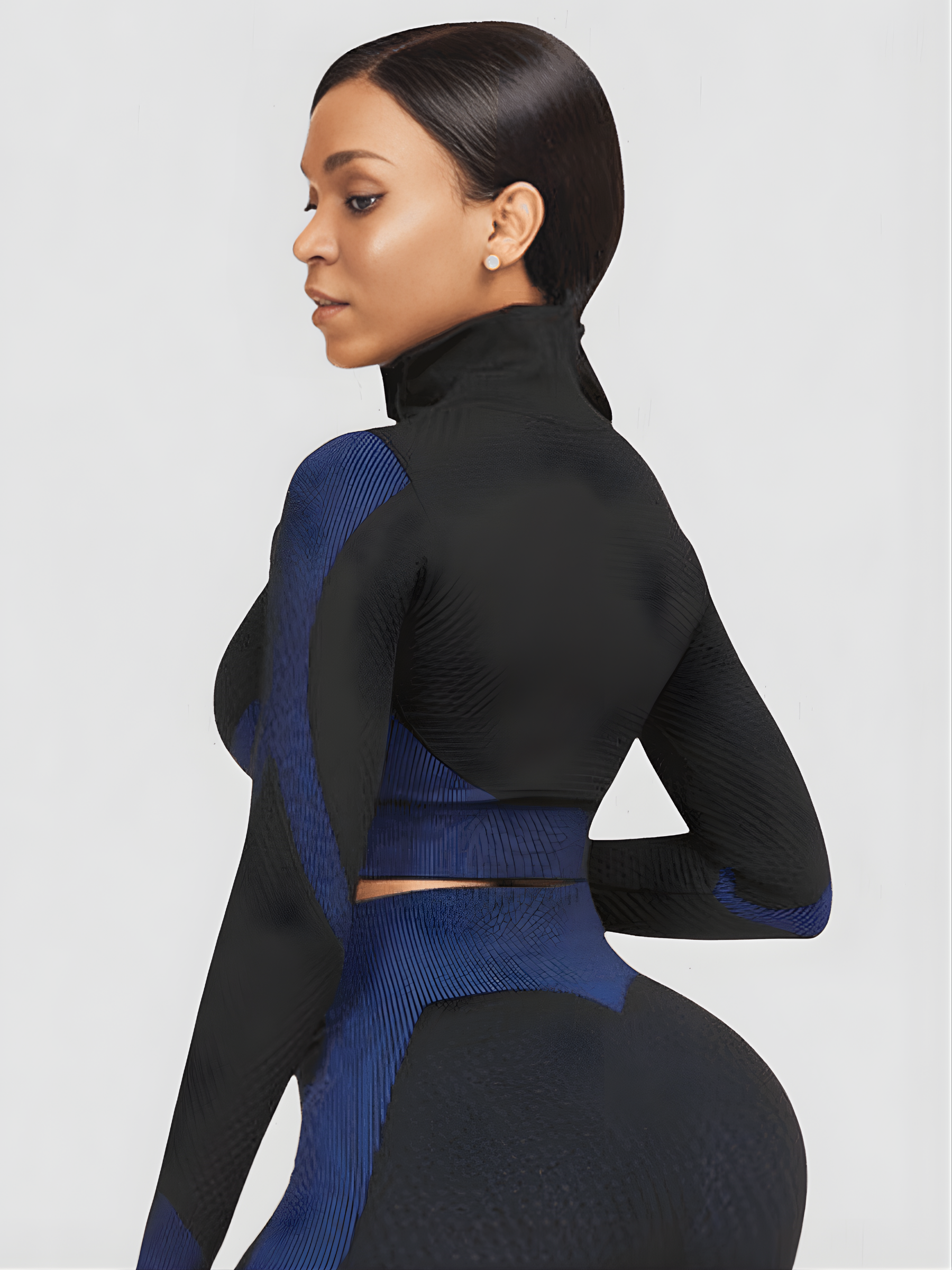 Woman wearing a blue and black zippered cropped activewear BBL jacket with matching leggings.