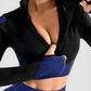 Woman wearing a blue and black zippered cropped activewear BBL jacket with matching leggings.
