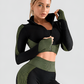 Woman wearing a green and black zippered cropped activewear BBL jacket with matching leggings.