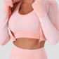 Woman wearing a pink zippered cropped activewear BBL jacket with a matching top.