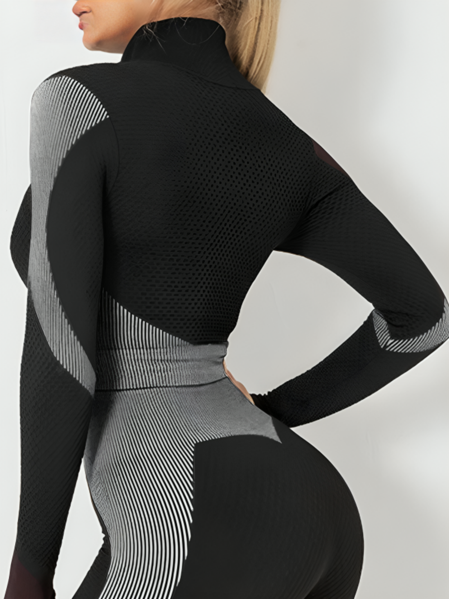 Woman wearing a black and gray color block activewear BBL jacket with matching leggings.