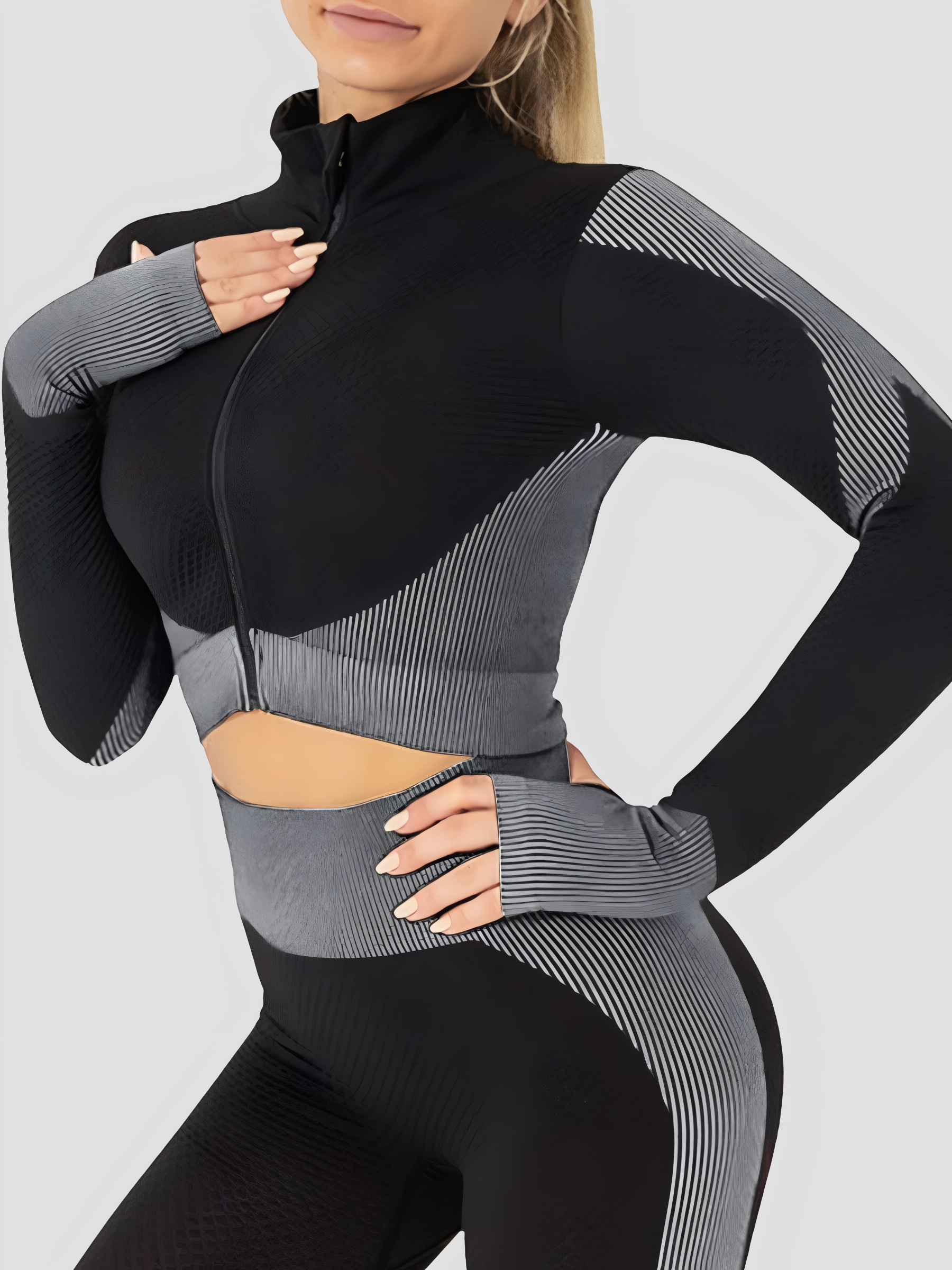 Woman wearing a black and gray cropped activewear BBL jacket with matching leggings.