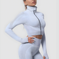 Woman wearing a silver gray zippered cropped activewear BBL jacket and matching leggings.