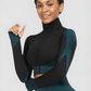 Woman wearing a teal and black zippered cropped activewear BBL jacket by BodyFlexx.
