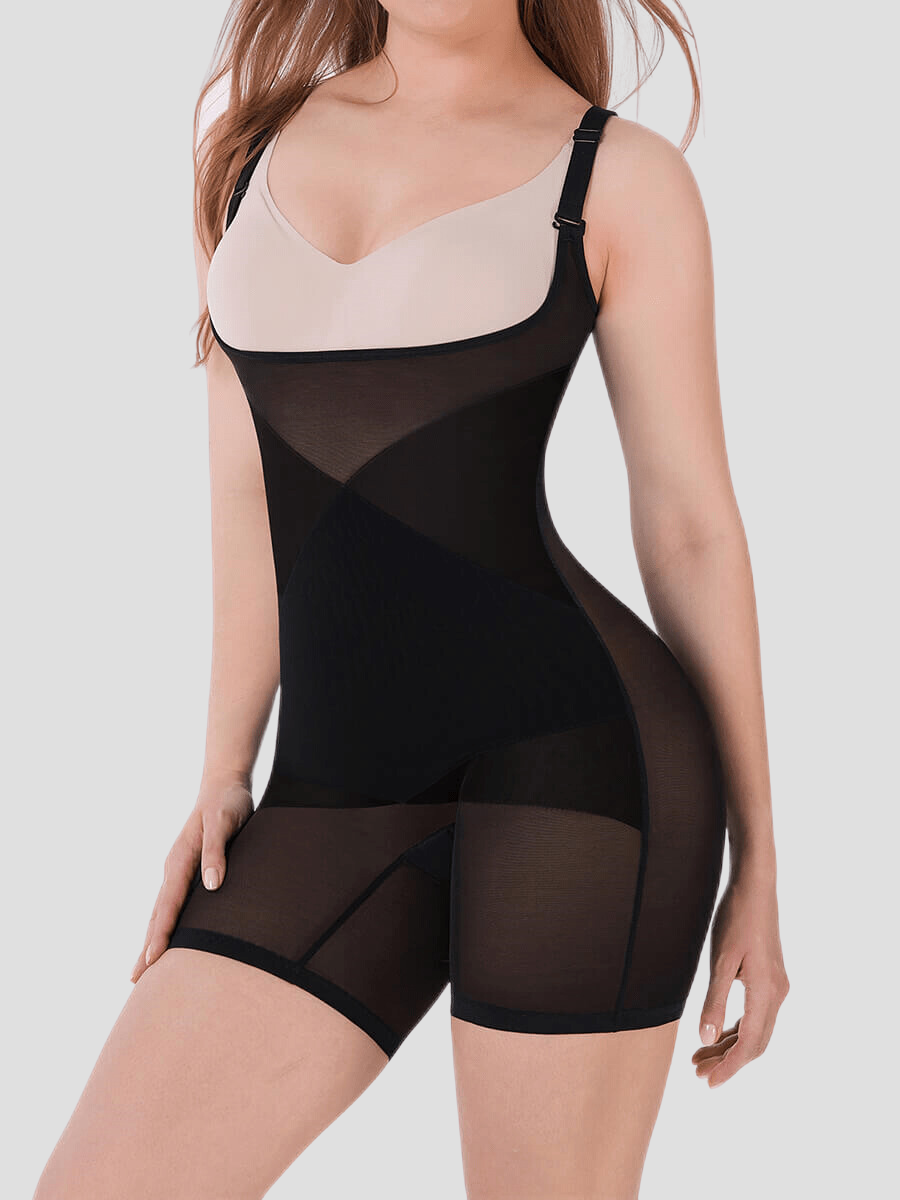 Woman wearing a black sheer open chest bodysuit shapewear and white bra posing to show her curves.