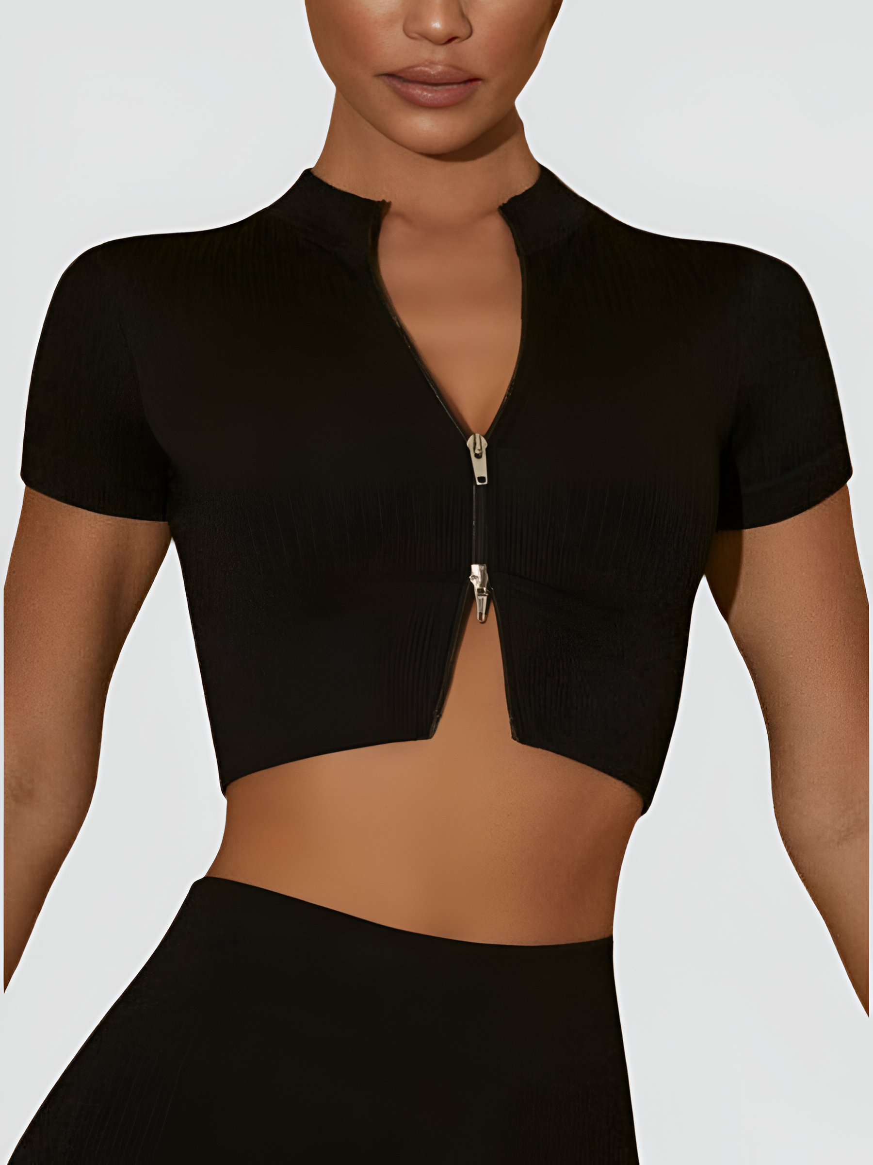 Woman wearing a black cropped ribbed activewear top with a double zipper and short sleeves by BodyFlexx.