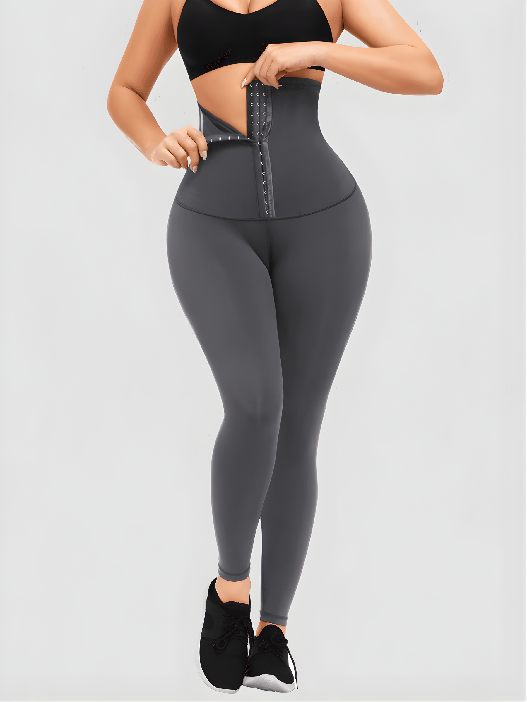 Woman wearing high-waisted blue waist training leggings with a corset-style closure to flatten her tummy and sculpt her curves.