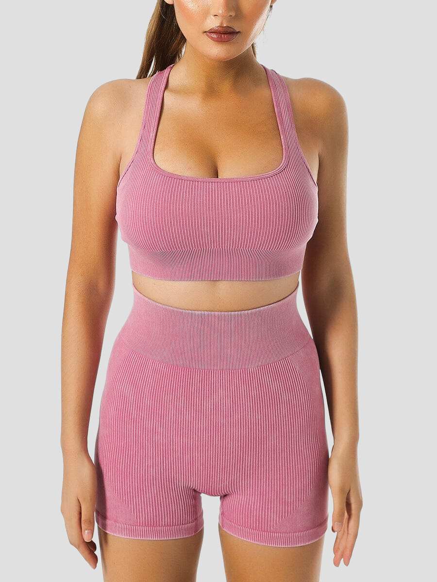 Woman wearing ribbed high-waisted pink activewear shorts and a matching sports bra designed by BodyFlexx.