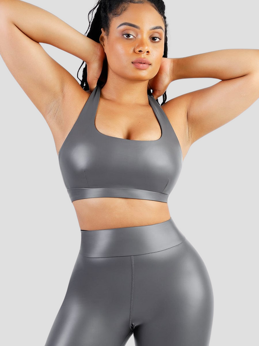 Woman wearing a flattering metallic silver sauna sports bra and matching leggings with her hands on her shoulders.