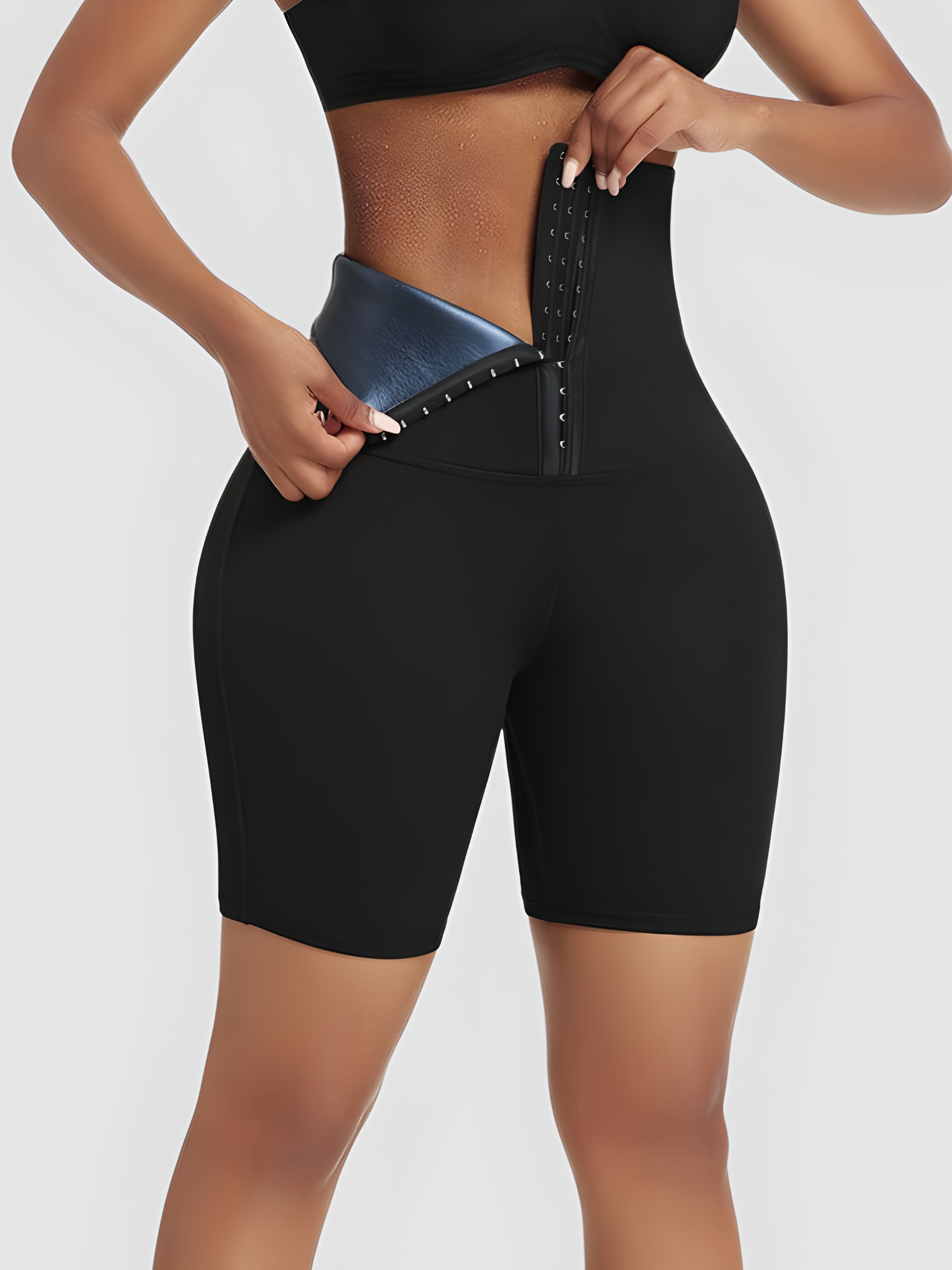 Woman wearing black BodyFlexx Waist-Training Sauna shorts with a corset closure showing a sweaty stomach after a good workout.