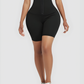 Woman wearing black mid-thigh waist-training sauna shorts with a corset closure.