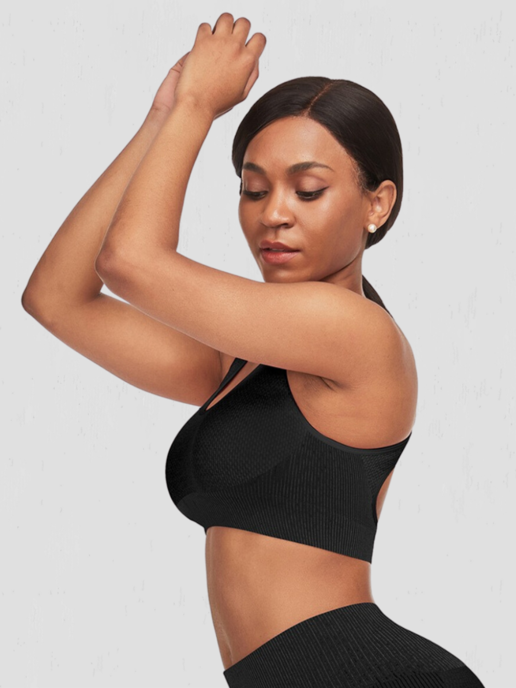 Woman wearing a padded black sports bra and matching leggings before a workout.