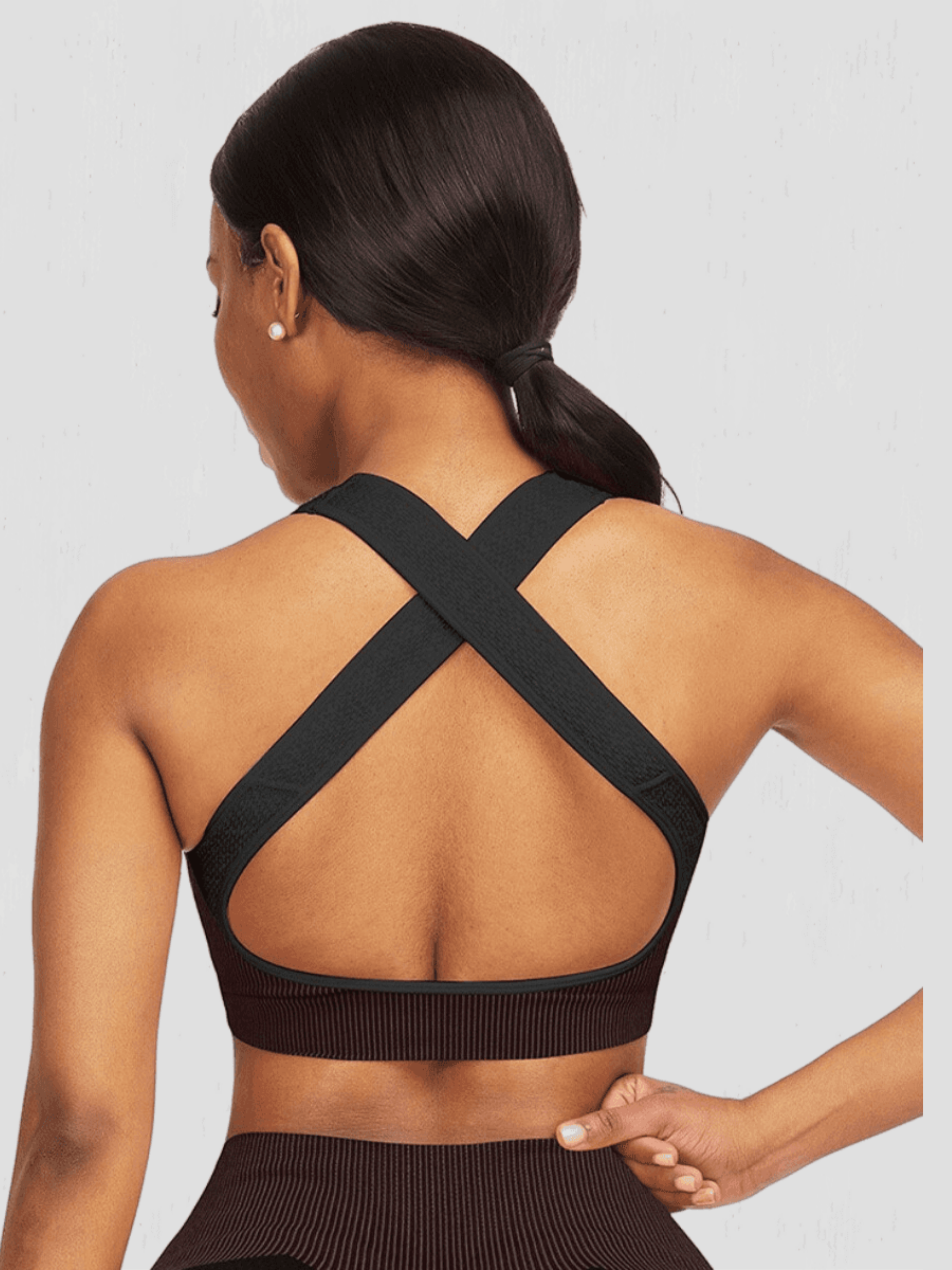 Woman wearing a black sports bra with criss-cross straps by BodyFlexx.