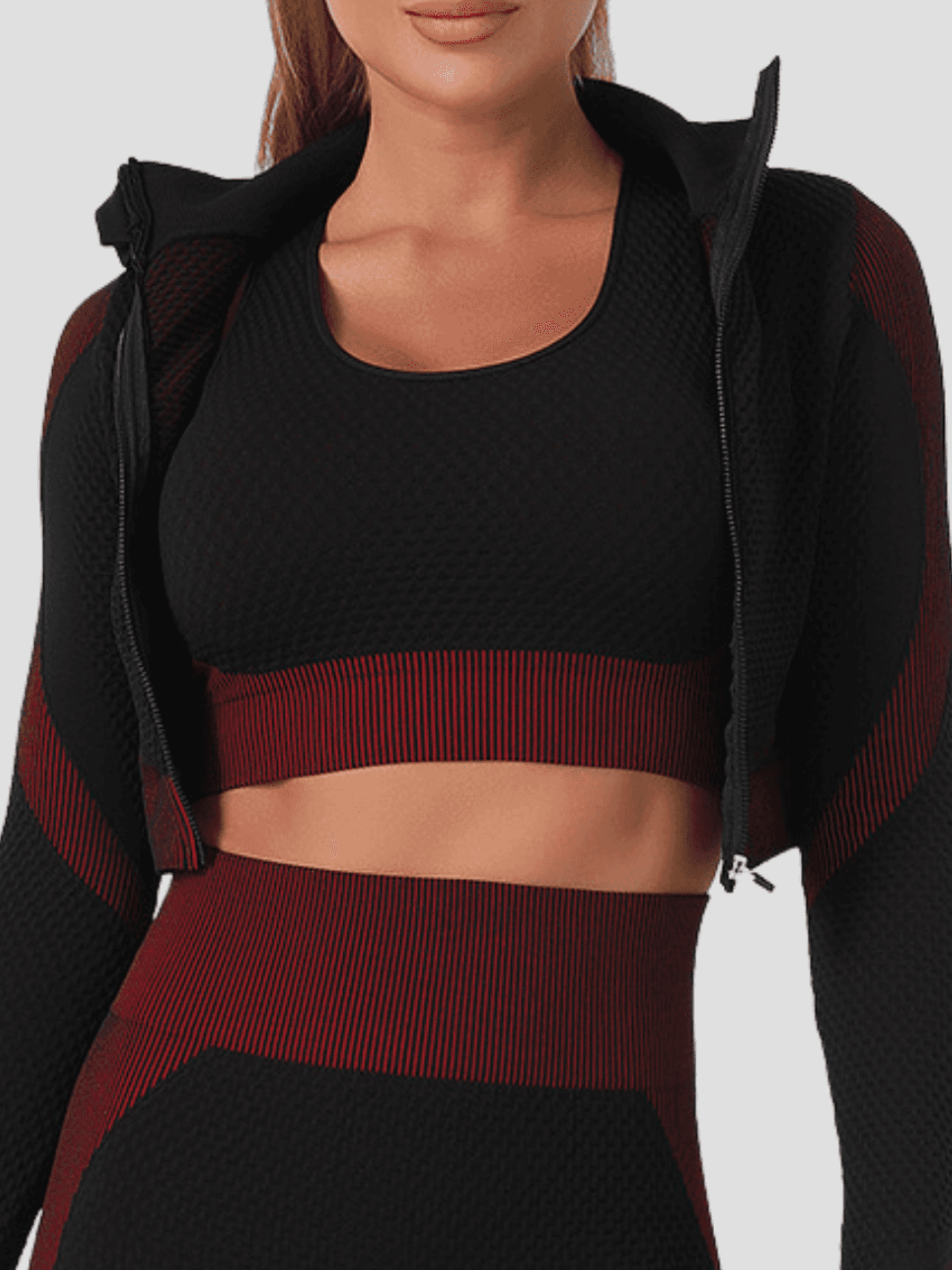 Woman wearing a padded black and fuchsia textured sports bra with matching leggings and activewear jacket.