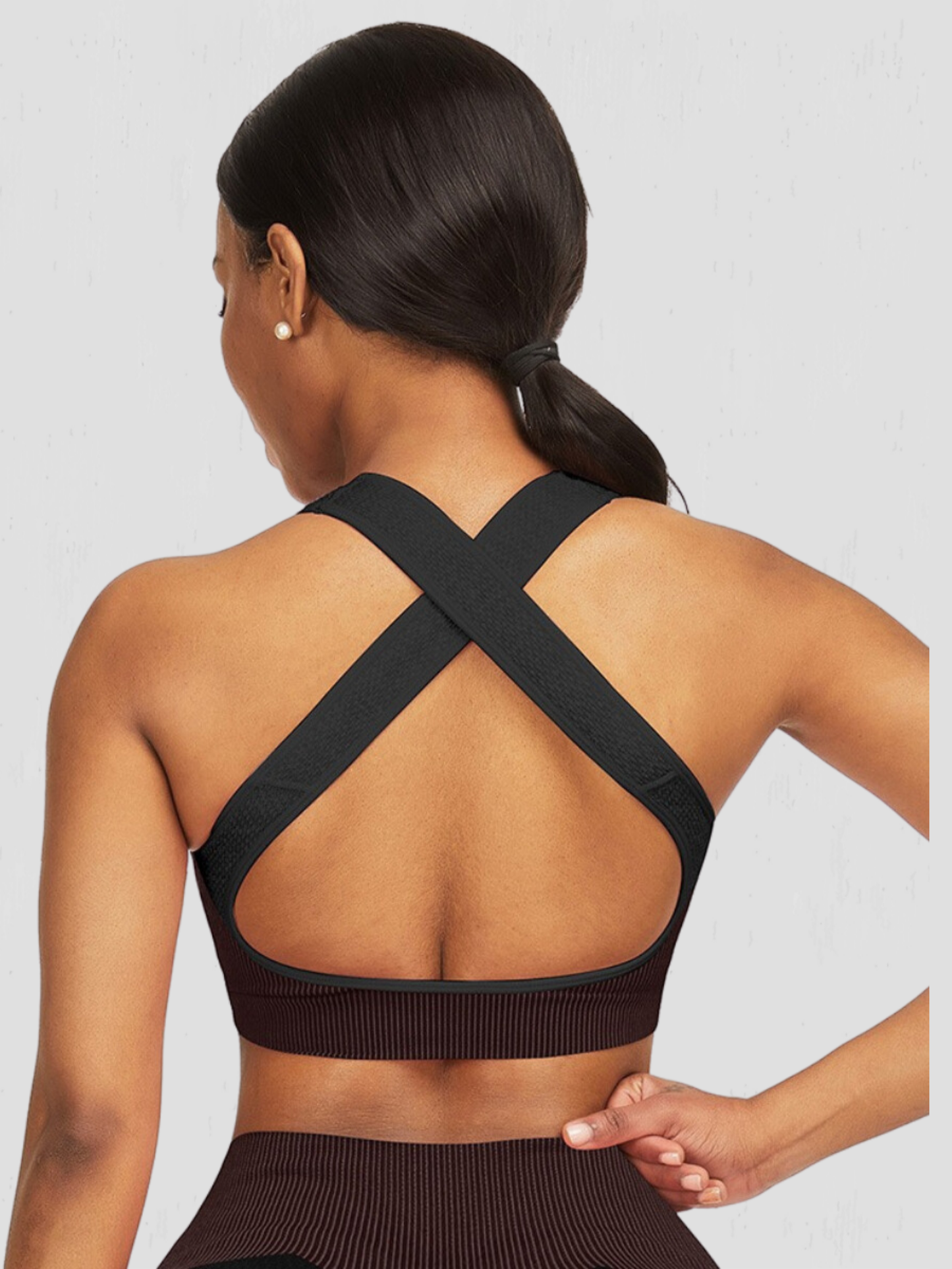Woman wearing a black and fuchsia sports bra with crisscross straps by BodyFlexx.