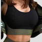 Woman wearing a black and green sports bra with matching leggings and jacket by BodyFlexx.