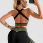 Woman taking a selfie wearing a green and black sports bra with crisscross straps.